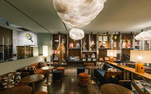 a restaurant with tables and stools in a room at Public House Bangkok, a Member of Design Hotels in Bangkok