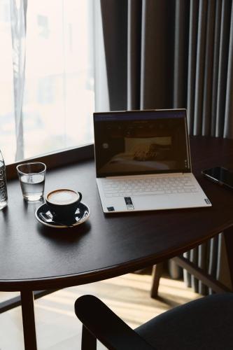 a laptop computer sitting on a table with a cup of coffee at Public House Bangkok, a Member of Design Hotels in Bangkok