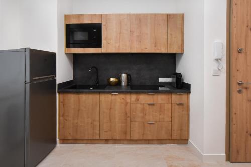 a kitchen with wooden cabinets and a black refrigerator at Zielona Aqua Dąbki in Dąbki