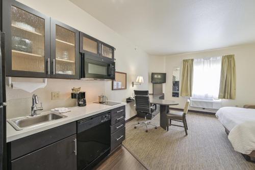 a hotel room with a kitchen and a bedroom at Affordable Suites of America Tulsa in Tulsa