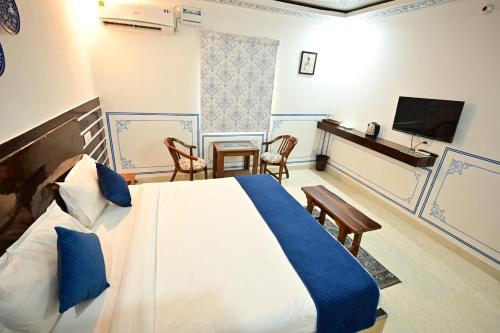 a bedroom with a bed and a table and a television at The castle crown - Hem Vilas Resort Ranthambhore in Sawāi Mādhopur