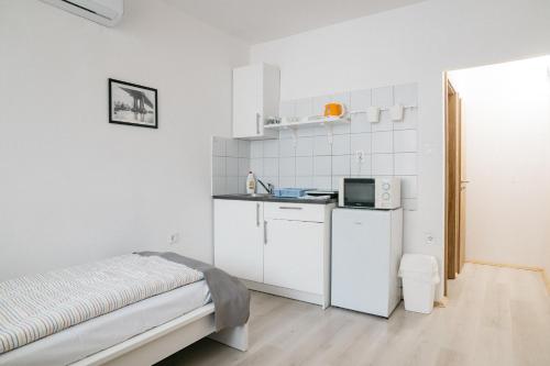 a small white kitchen with a sink and a refrigerator at Tavaszház Apartmanok in Balatonfüred