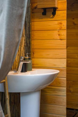 La salle de bains est pourvue d'un lavabo blanc et de murs en bois. dans l'établissement Palom'bolla, à Porto-Vecchio
