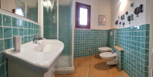 a green tiled bathroom with a sink and a toilet at Apartment with garden in Budoni