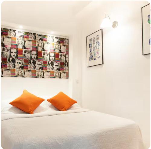 - un lit avec deux oreillers orange dans l'établissement stay-cannes- 1 Bedroom beach & congress apartment, à Cannes