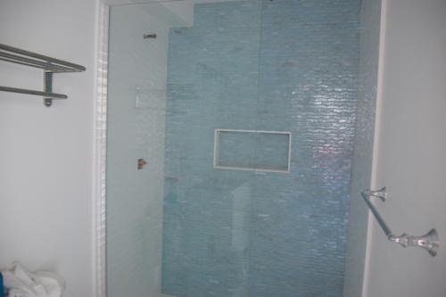 a shower with a blue tile wall in a bathroom at Rhea's Inn by the Sea in Middletown