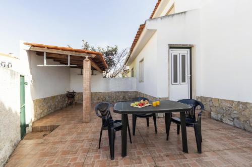a patio with a table and chairs on a brick patio at Moradia Marques in Nazaré