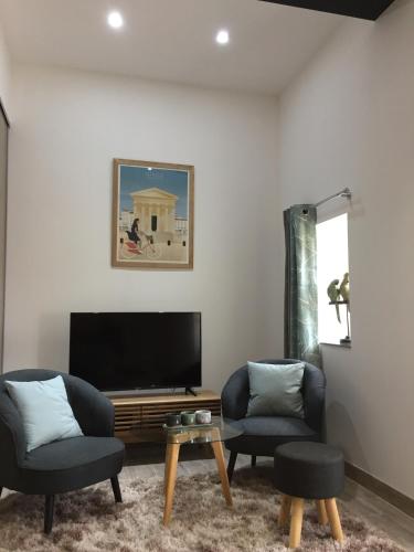 - un salon avec deux chaises et une télévision à écran plat dans l'établissement Studio centre ville avec vue sur les toits, à Nîmes