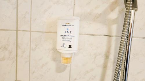 a bottle of sunscreen hanging on a wall in a bathroom at Hotel Dorfkrug Büsum in Büsum