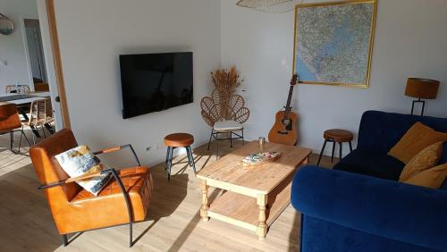 un salon avec un canapé bleu et une table dans l'établissement New house near ria and beach, à Plouhinec