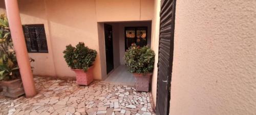 un bâtiment avec deux plantes en pot devant une porte dans l'établissement La maison de Kalabancoura, à Bamako