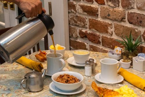 a person pouring coffee into cups on a table at The Marshall House, Historic Inns of Savannah Collection in Savannah