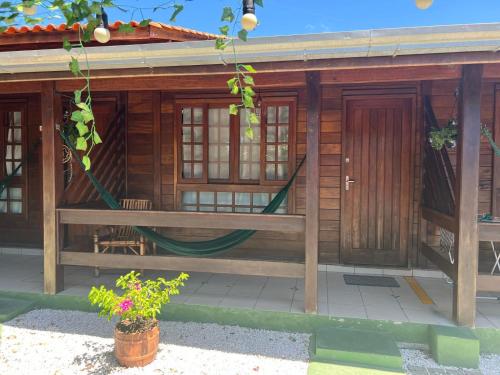 ein Holzhaus mit einer Hängematte davor in der Unterkunft Residencial Alvorada in Bombinhas