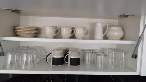 a shelf with many glass jars and vases on it at MG Apartament Elfów in Tychy