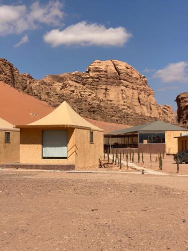 a building in the desert with a mountain in the background at Wadi Rum Santa Camp in Wadi Rum