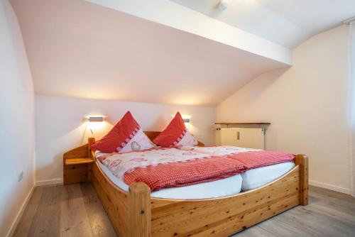 - une chambre avec un lit en bois et des oreillers rouges dans l'établissement Ferienwohnung Bamberger Gipfelblick, à Hopferau