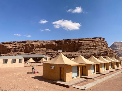 a row of tents in the desert with a mountain at Wadi Rum Santa Camp in Wadi Rum