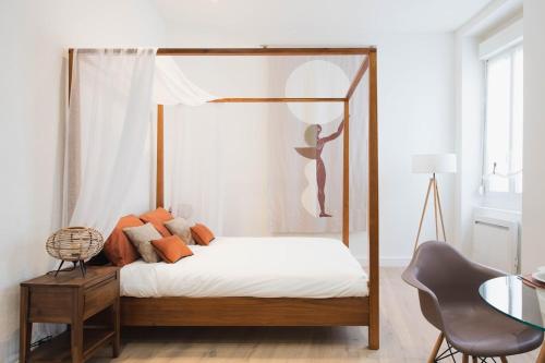 - une chambre avec un lit à baldaquin et des oreillers orange dans l'établissement Appartement idéalement situé dans l'Ecusson, à Nîmes