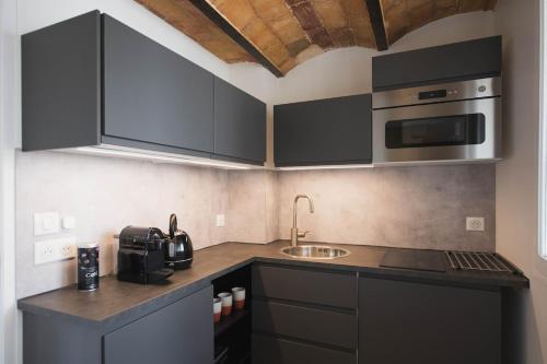 - une cuisine avec des placards noirs et un évier dans l'établissement Appartement idéalement situé dans l'Ecusson, à Nîmes