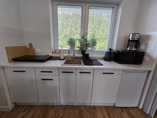 a kitchen with white cabinets and a sink and a window at Apartament Danuta Mrągowo in Mrągowo