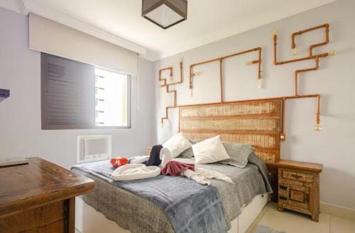 een slaapkamer met een bed met een houten hoofdeinde bij Flat ao lado do Mar Four Season in Guarujá