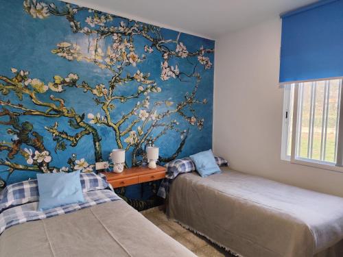 a bedroom with two beds and a blue wall at La Casa de los Alemanes in Gaibiel