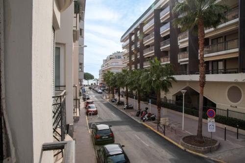 une rue avec des voitures garées et des palmiers dans une ville dans l'établissement 1-Br Apartment in Cannes Walk to the Beach, à Cannes