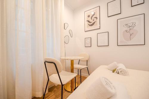 - une chambre blanche avec 2 lits et 2 chaises dans l'établissement Charming studio in the Marais, à Paris