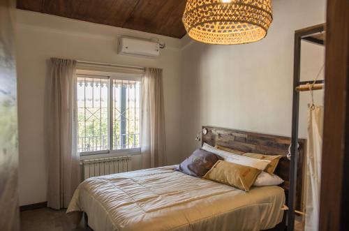 une chambre avec un lit, une fenêtre et un lustre dans l'établissement Casa entre viñedo con vista a la Cordillera, à Las Compuertas