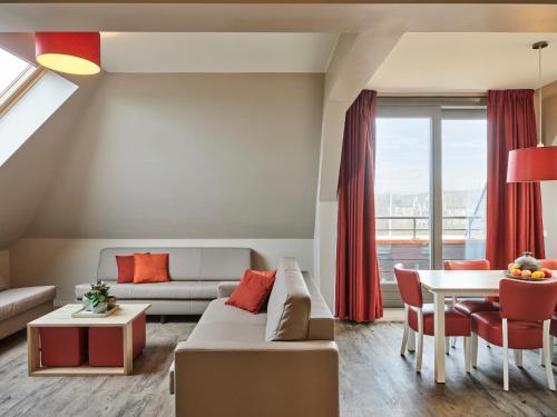 a living room with a couch and a table at Holiday Suites Westende - Middelkerke in Middelkerke