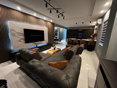 a living room with a leather couch and a television at Seaside Serenity Maisonette - Private Pool in St. Paul's Bay