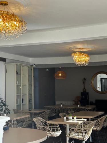 a restaurant with tables and chairs and chandeliers at Hotel Eden in Saint Malo