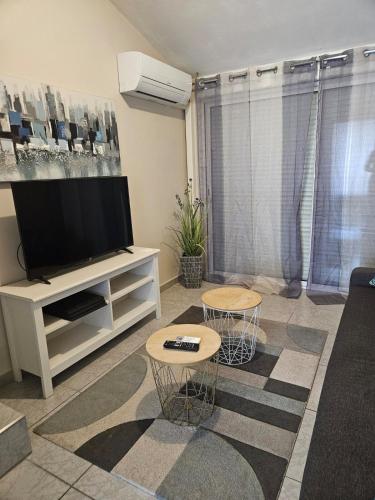 - un salon avec une télévision à écran plat et deux tables dans l'établissement Joli studio piscine climatisé, aux Angles (Gard)