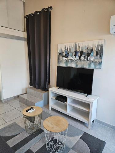 - un salon avec une télévision à écran plat et deux tabourets dans l'établissement Joli studio piscine climatisé, aux Angles (Gard)