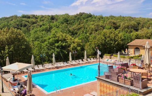 a pool at a resort with chairs and umbrellas at Residence with swimming pool in Monteverdi Marittimo in Monteverdi Marittimo