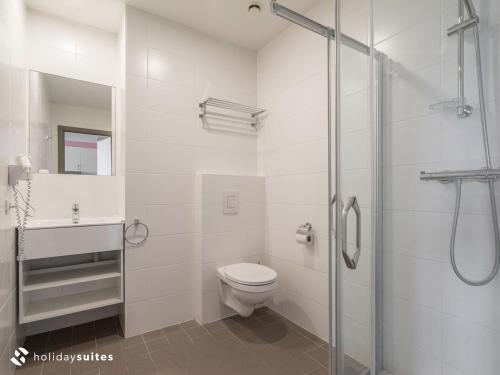 a bathroom with a toilet and a glass shower at Holiday Suites Westende - Middelkerke in Middelkerke