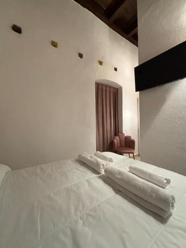 a bedroom with a bed with white sheets and a chair at La Maison De Poupée in Bari