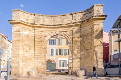 a man walking past an archway in a building at Studio du Clocher - Centre Historique, Cosy, Wifi, 2 personnes in Istres