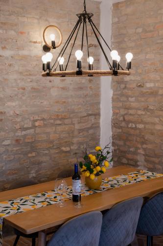 a dining room table with a bottle of wine and a chandelier at Anno 1859 Vendégház in Bátaszék
