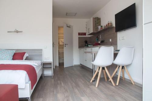a bedroom with a bed and two white chairs at Apartment 10 in Igersheim