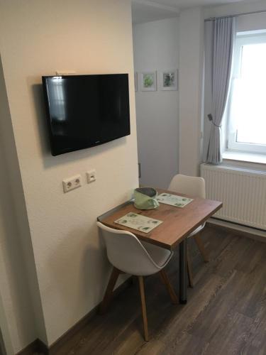 a room with a table and a television on the wall at Apartment 04 in Igersheim