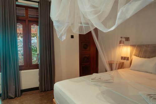 a bedroom with a bed with white sheets and a window at Hill Top Haven Hiriketiya in Dickwella