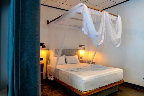 a bedroom with a canopy bed with white drapes at Hill Top Haven Hiriketiya in Dickwella