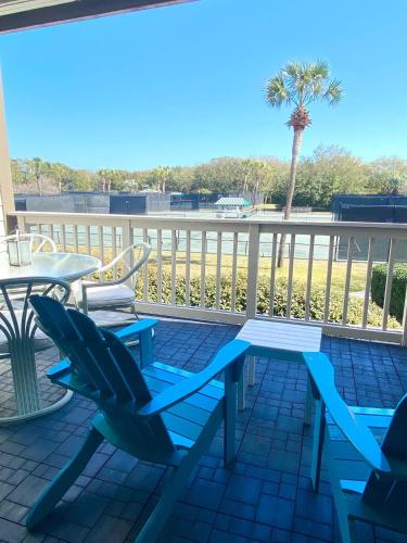 a patio with blue chairs and a table and a palm tree at 1617 Live Oak in Johns Island