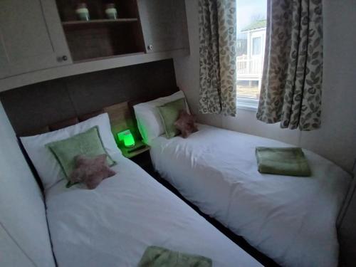 two twin beds in a room with a window at Serenity - Luxury Hot Tub, Sunnymede, Fantasy Island, , Ramped Access, Parking, Dog Friendly in Ingoldmells