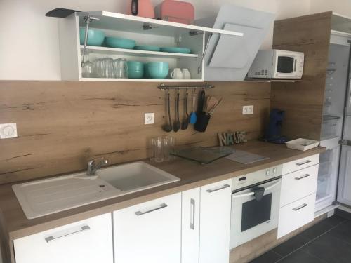 cocina con armarios blancos, fregadero y encimera en Appartement cosy mer, en Le Grau-du-Roi