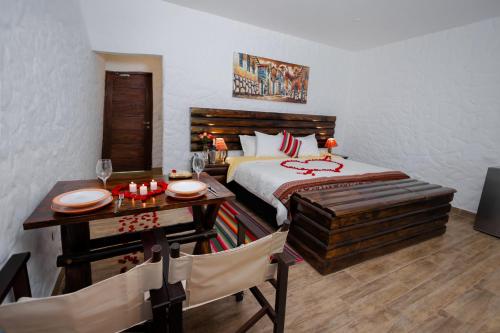 a bedroom with a bed and a table and a dining room at RUSTICA HOTELES CUSCO Urubamba in Pachar