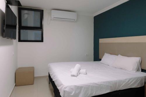 a bedroom with a white bed with a towel on it at Rich Boutique Hotel in Eilat