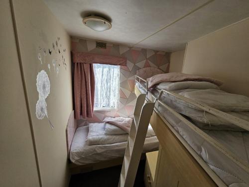 a small room with two bunk beds and a window at The Hive on The Chase Ingoldmells in Skegness