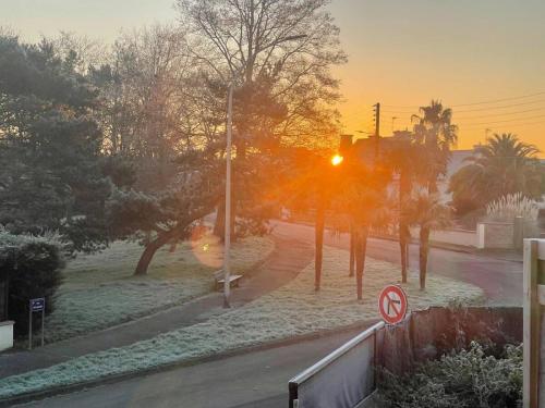 a sunset over a street with trees and a street sign at Appartement et terrasse Dinard 4p in Dinard